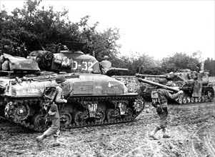 American tanks pass destroyed German equipment in Normandy, July 1944