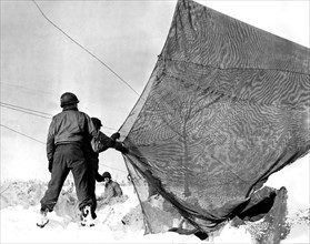 American soldiers use camouflage screen in Germany, January 25, 1945