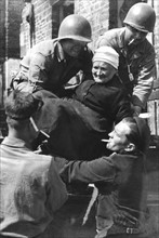 Les soldats américains apportent leur aide à une femme âgée, dans la région de Tessy-sur-Vire.
(Août 1944)