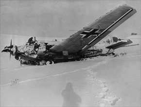 American soldier examines knocked down German plane near Asselborn, January 1945