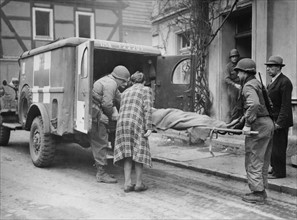 Soldats américains apportant leur aide à un civil allemand à Bad Godesberg
(9 mars 1945)