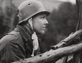 Wounded U.S. soldier aims at enemy sniper in Scharfenberg, April 2, 1945