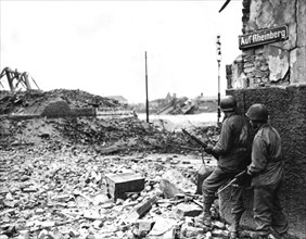 Soldats de l'infanterie américaine postés à un coin de rue à Cologne, en Allemagne. (6 mars 1945)