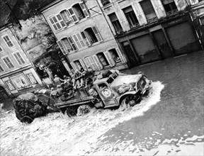 Les troupes américaines avancent à travers les rues inondées de Rambervillers.