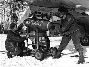 Aviateurs d'une unité de chasseurs-bombardiers installant une bombe sous un bombardier P-47 Thunderbolt. (7 février 1945)