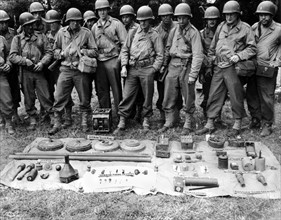 Soldats américains devant un échantillonage de mines allemandes en Normandie. (Juillet 1944)