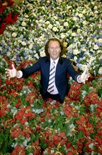 (dpa) - Dutch star violinist Andre Rieu smiles while standing in a sea of artificial flowers in