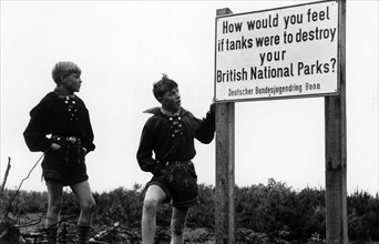 Two boys standing next to a sign against the devastation of nature by British troops