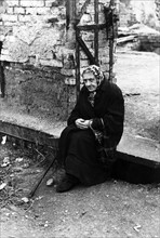 Post-war Germany: Poor elderly woman in front of destroyed house