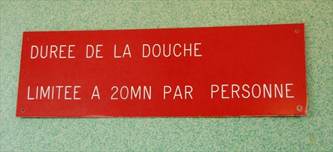 Ein Hinweisschild mit der Aufschrift: "Duree de la douche limitee a 20...