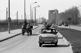 Carriage and Trabant car on a barely used street near a district of prefabricated buildings east of Berlin