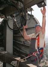 ServicetechnikerWolfgang Jahnke ist vorschriftsmässig mit einem Geschirr gesichert, als er damit beschäftigt ist, in 330 Meter Höhe auf dem Berliner Fernsehturm einen Richtfunkstrahler zu demontieren