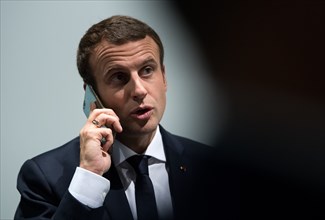 Emmanuel Macron talks on his telephone as he walks along a corridor in the exposition halls in Hamburg