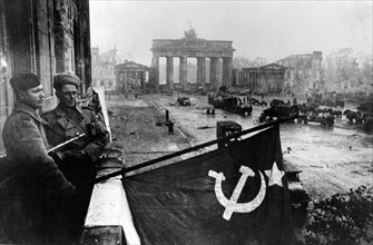 Red Army soldiers hoist the Soviet flag from a balcony of the renowned Hotel Adlon, Berlin