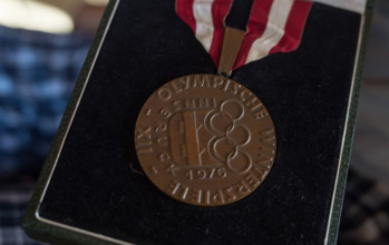 Former professional ice hockey player Lorenz Funk presents his bronze medal he won in the 1976