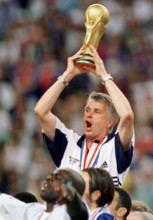 French soccer coach Aime Jacquet cheers and laughs while he holds the World Cup trophy in his hands