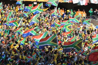South African supporters wave flags during the opening match between South Africa and Mexico at the