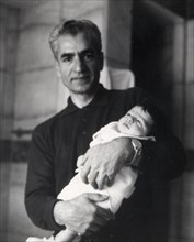 Mohammad Reza Shah Pahlavi holding his son in his arms (1963)