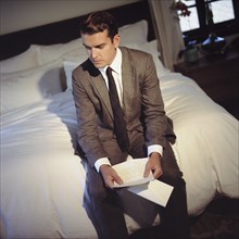 Man Sitting in Bedroom Reading Letter