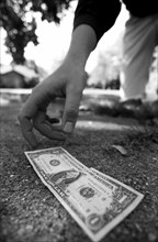 Man Picking Up Dollar Bill From Ground