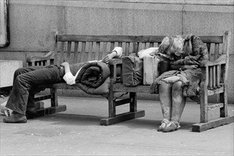 Homeless Man and Woman Sleeping on Park Bench