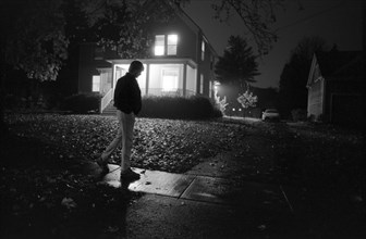 Man Walking Past House at Night
