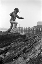 Boy Jumping on Rocks Along Shore