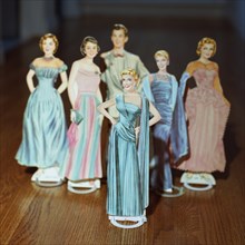 Female Paper Dolls in Evening Gowns With One Male Paper Doll in Background