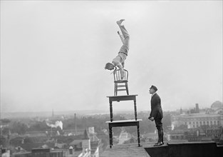 Jug Reynolds Performing Daredevil Balancing Act on High Cornice above Ninth Street N.W. Washington DC, USA, Harris & Ewing, 1917