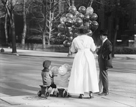 Woman with Two Children Buying Balloons from Vendor, USA, Harris & Ewing, 1919