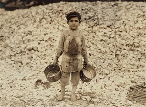 5-year-old Boy Working as Shrimp Picker with Large Mound of Oyster Shells in Background, Biloxi, Mississippi, USA, Lewis Hine, 1911