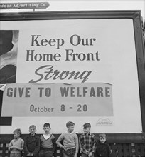 Group of Boys under Billboard, their Fathers work in nearby Defense Plants, near Lititz, Pennsylvania, USA, Marjorie Collins for Office of War Information, November 1942