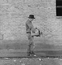 Cotton Picker Carrying Farm Security Administration (FSA) Grant of Food and Necessities to to his Family at FSA Migrant Camp, Bakersfield, California, USA, Dorothea Lange for Farm Security Administrat...