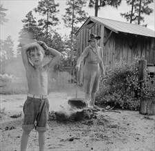 Woman Boiling Wash Water With Son Standing Nearby on Farm, Escambia Farms, Florida, USA, John Collier for Farm Security Administration, June 1942