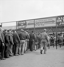 Workers Lining up Before Time Clock at Changing of Shifts, Bethlehem-Fairfield, Shipyards, Baltimore, Maryland, USA, Arthur S. Siegel for Office of War Information, May 1943