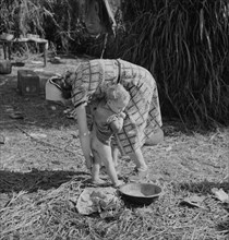 Woman Packinghouse Worker Cleaning her Young Child with Filthy Water from Nearby Canal, Belle Glade Florida, USA, Marion Post Wolcott for Farm Security Administration,
