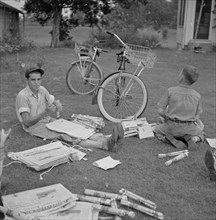 Two Boys Folding Newspapers before Starting their Afternoon Deliveries, near Natchitoches, Louisiana, USA, Marion Post Wolcott for Farm Security Administration, July 1940