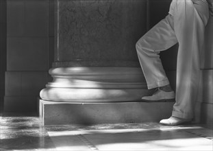 View of Man's Legs in Cuffed Trousers Standing at Column Base, State Capitol Building, Lincoln, Nebraska, USA, by Samuel H. Gottscho, June 1934