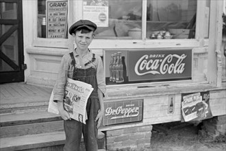 Farm Boy Selling Newspapers in front of General Store, Irwinville Farms, Georgia, John Vachon for Farm Security Administration, May 1938