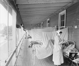 Masked Nurse at the Head of a Row of Beds Treating Patient during Influenza Pandemic, Walter Reed Hospital, Washington DC, USA, Harris & Ewing, 1918
