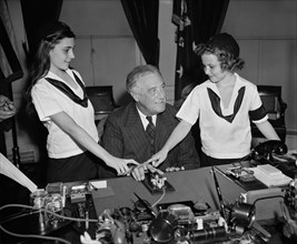 U.S. President Franklin Roosevelt with Two Camp Fire Girls Pressing Telegraph Key to Light Crossed Logs and Flame Lamp in Organization's New National Headquarters in New York City, Washington DC, USA,...