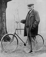 John D. Rockefeller (1839-1937), Portrait standing with Bicycle, 1913