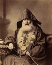 Armenian Patriarch of Jerusalem, Harootiun Vehabedian, Seated Portrait Wearing Hooded Vestment, Adorned with Crosses and other Medals, Holding a Strand of Beads, Jerusalem, American Colony Photo Depar...