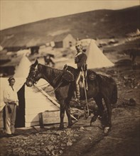 Full-length Portrait of British 5th Dragoon Guards Captain in Uniform, Seated on Horse with another Man Standing at Head of Horse, Tent and Huts in Background, Crimean War, Crimea, Ukraine, by Roger F...