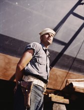 Coast Guard Sentry Standing Watch over New Torpedo Boat Under Constructions at Shipyard, Higgins Industries, Inc., New Orleans, Louisiana, USA, Howard R. Hollem for Office of War Information, July 194...