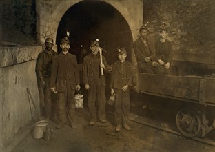 Coal Miners with Young Trapper Boy in Center, Full-Length Portrait at Mine Entrance, Gary, West Virginia, USA, Lewis Hine for National Child Labor Committee, September 1908