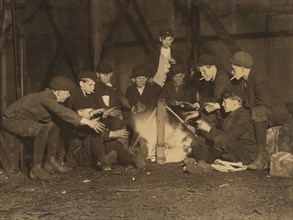 Gang of Newsboys Staying Warm over Campfire in Corner Lot at Night, Jefferson Street near Olive, St. Louis, Missouri, USA, Lewis Hine for National Child Labor Committee, May 1910