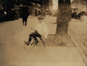 William "Willie" Tear, 5-year-old Newsboy, Portrait Sitting on Tricycle with Newspapers, Washington DC, USA, Lewis Hine for National Child Labor Committee, April 1912