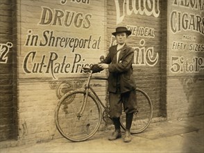 Howard Williams, 13 years old, Delivery Boy for Drug Company, works from 9:30 a.m. to 10:30 p.m., Full-Length Portrait with Bicycle, Shreveport, Louisiana, USA, Lewis Hine for National Child Labor Com...
