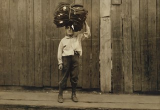 Young Boy Carrying Load of Clothes on his Head, Full-Length Portrait, Boston, Massachusetts, USA, Lewis Hine for National Child Labor Committee, August 1912
